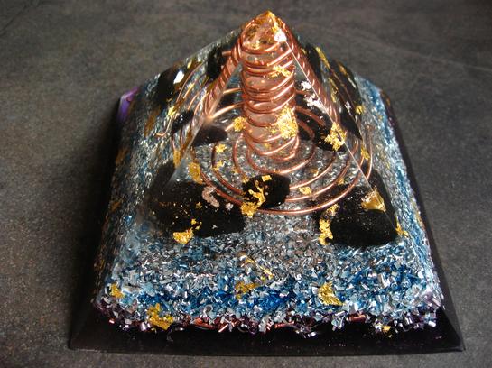 <h1>Pyramide Nombre d'Or</h1><br/><h4>11cm de Base, 7cm de Hauteur, poids 400g.<br/><br/> Composée de Shungite, Tourmaline, Imprégnée des Flammes Violette et Bleue.<br/><br/>Intense générateur de Prana amplifié par l'Onde de Forme, Grande Protection contre les Ondes, idéale pour les Pièces de Vie, Bureau...<br/><br/>Magnifique Encrage par action sur les Chakras de Base et Sacré<br/>Pour Ma part, En Méditation, elle m'isole d'une façon extraordinaire du Monde extérieur, en établissant une Barrière autour du corps. Le Lâcher-prise est nettement Facilité, les Sensations Grandement Amplifiées...</h4>