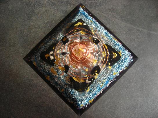 <h1>Pyramide Nombre d'Or</h1><br/><h4>11cm de Base, 7cm de Hauteur, poids 400g.<br/><br/> Composée de Shungite, Tourmaline, Imprégnée des Flammes Violette et Bleue.<br/><br/>Intense générateur de Prana amplifié par l'Onde de Forme, Grande Protection contre les Ondes, idéale pour les Pièces de Vie, Bureau...<br/><br/>Magnifique Encrage par action sur les Chakras de Base et Sacré<br/>Pour Ma part, En Méditation, elle m'isole d'une façon extraordinaire du Monde extérieur, en établissant une Barrière autour du corps. Le Lâcher-prise est nettement Facilité, les Sensations Grandement Amplifiées...</h4>